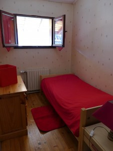 Cette chambre est meublée avec un lit, un bureau et une chaise, le tout dans des tons de rouge et de blanc.