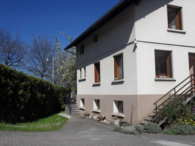 Cette maison individuelle, de construction traditionnelle, possède un étage et est dotée de fenêtres à volets en bois.